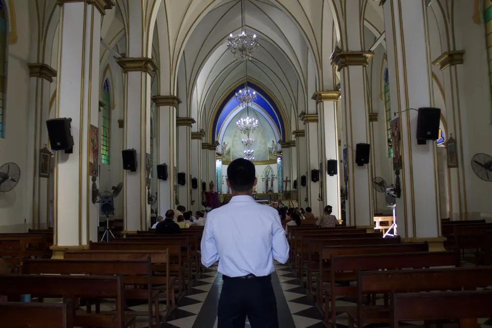 Joaquín Caballero from behind, walking down the nave of a church